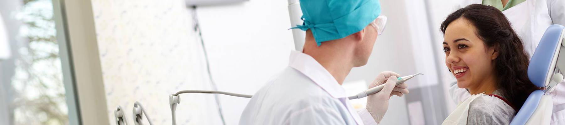 Woman in dental exam room smiling, dentist about to exam